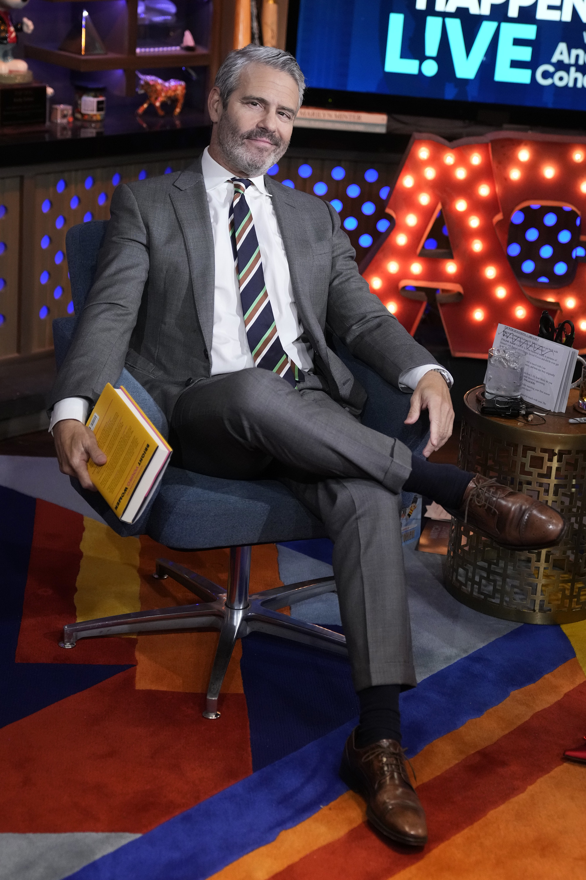 Close-up of Andy smiling, seated, and wearing a suit and tie on the set of Watch What Happens With Andy Cohen Live