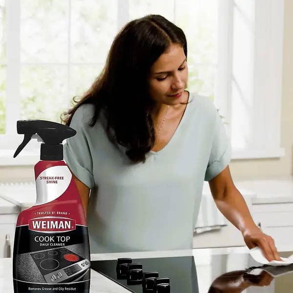 Woman cleaning stove with cook top cleaner