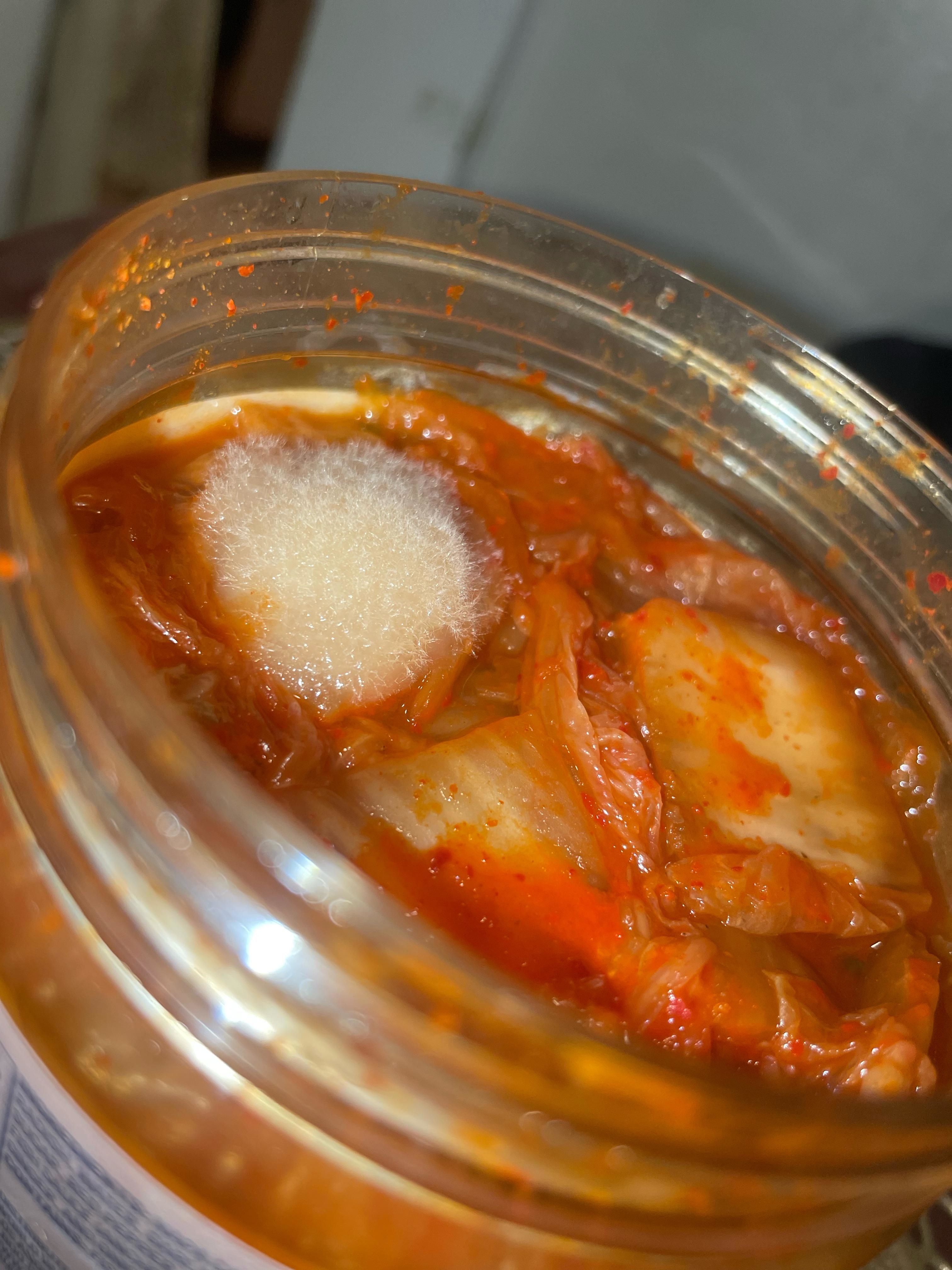 a jar of kimchi with mold growing on top