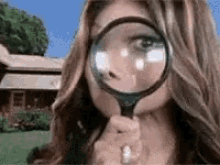 GIF of woman holding up a magnifying glass to her face
