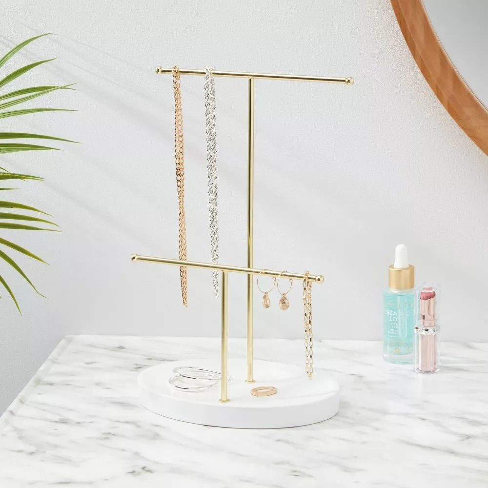 the jewelry stand on a bathroom counter with necklaces and earrings