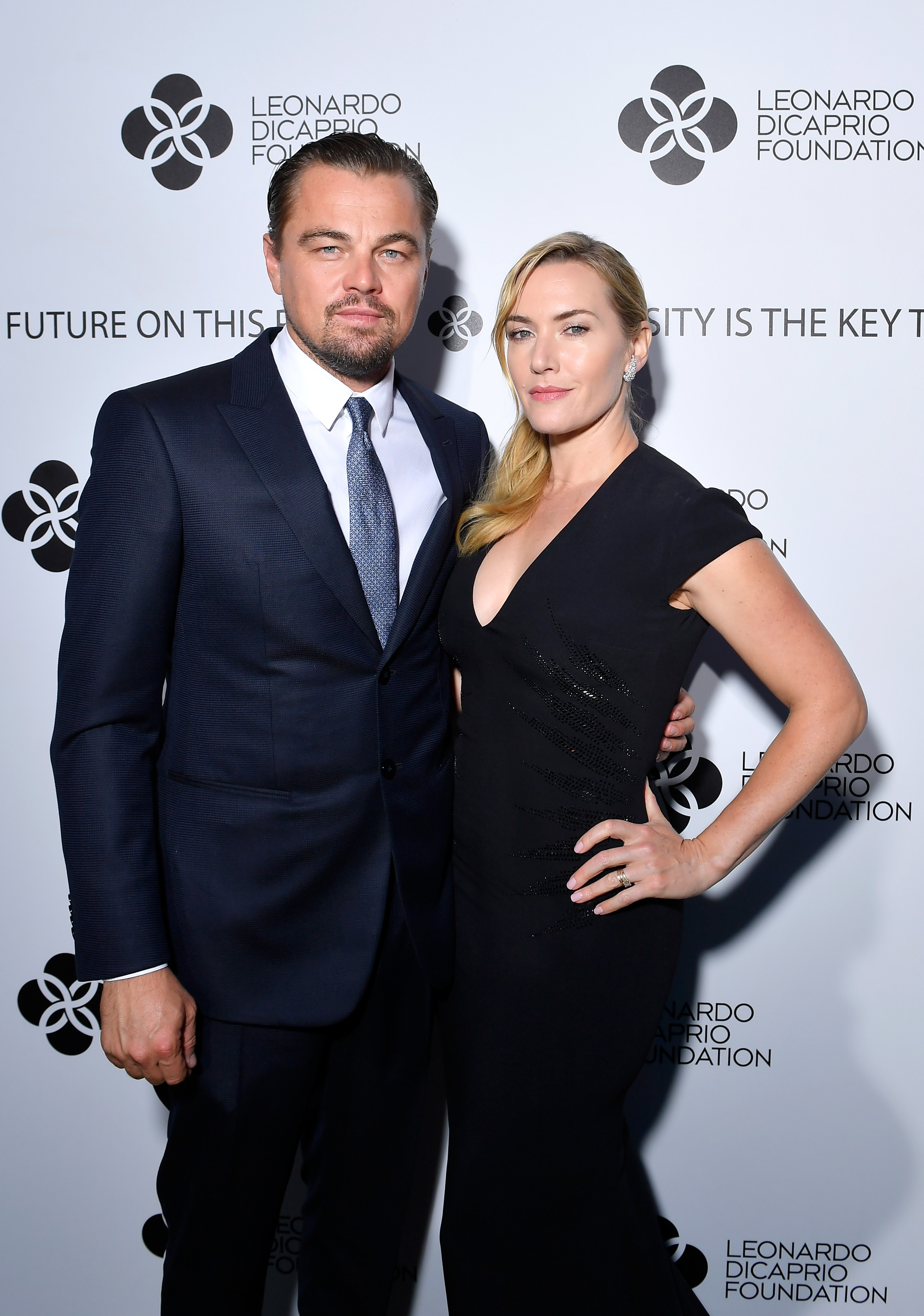 Leo in a suit and tie and Kate in a long sleeveless dress at a media event