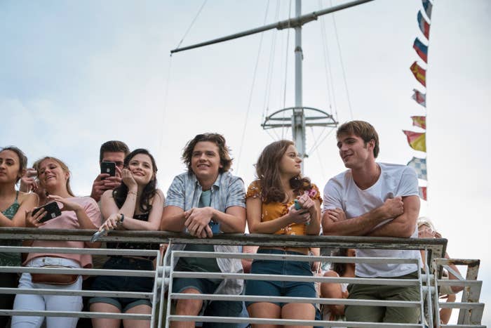 Jacob Elordi and Joey King stand next to a railing with a crowd of people in a scene from &quot;The Kissing Booth&quot;