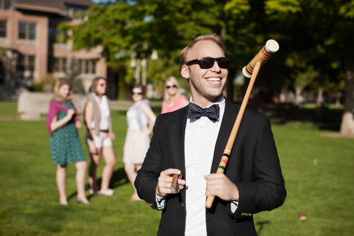 A rich man smiling with a cigar in one hand and a croquet mallet in the other