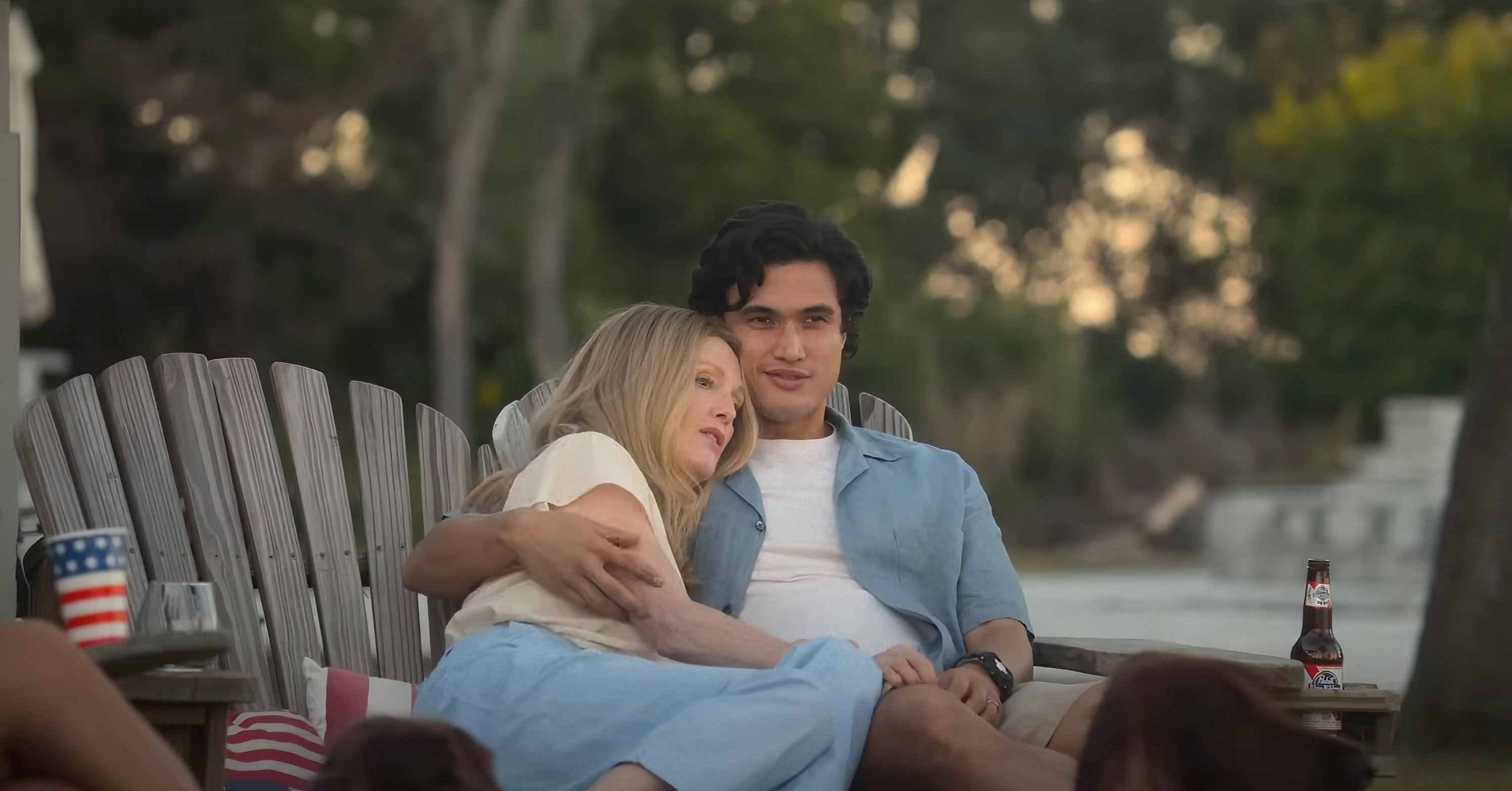 Julianne and Charles cuddling on garden chairs in a scene from from &quot;May December&quot;