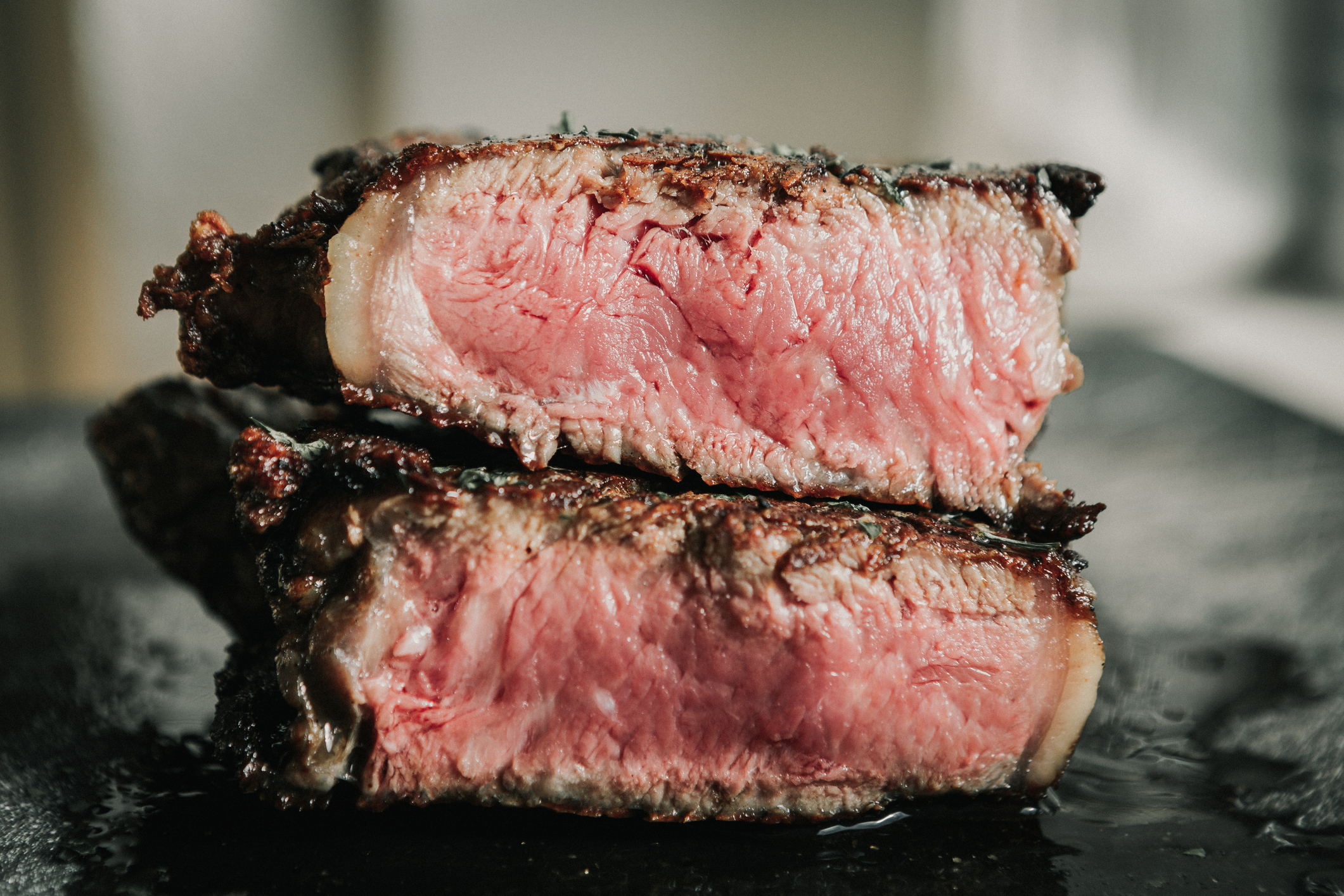 A close-up image of steak, cut open, revealing a medium rare cook