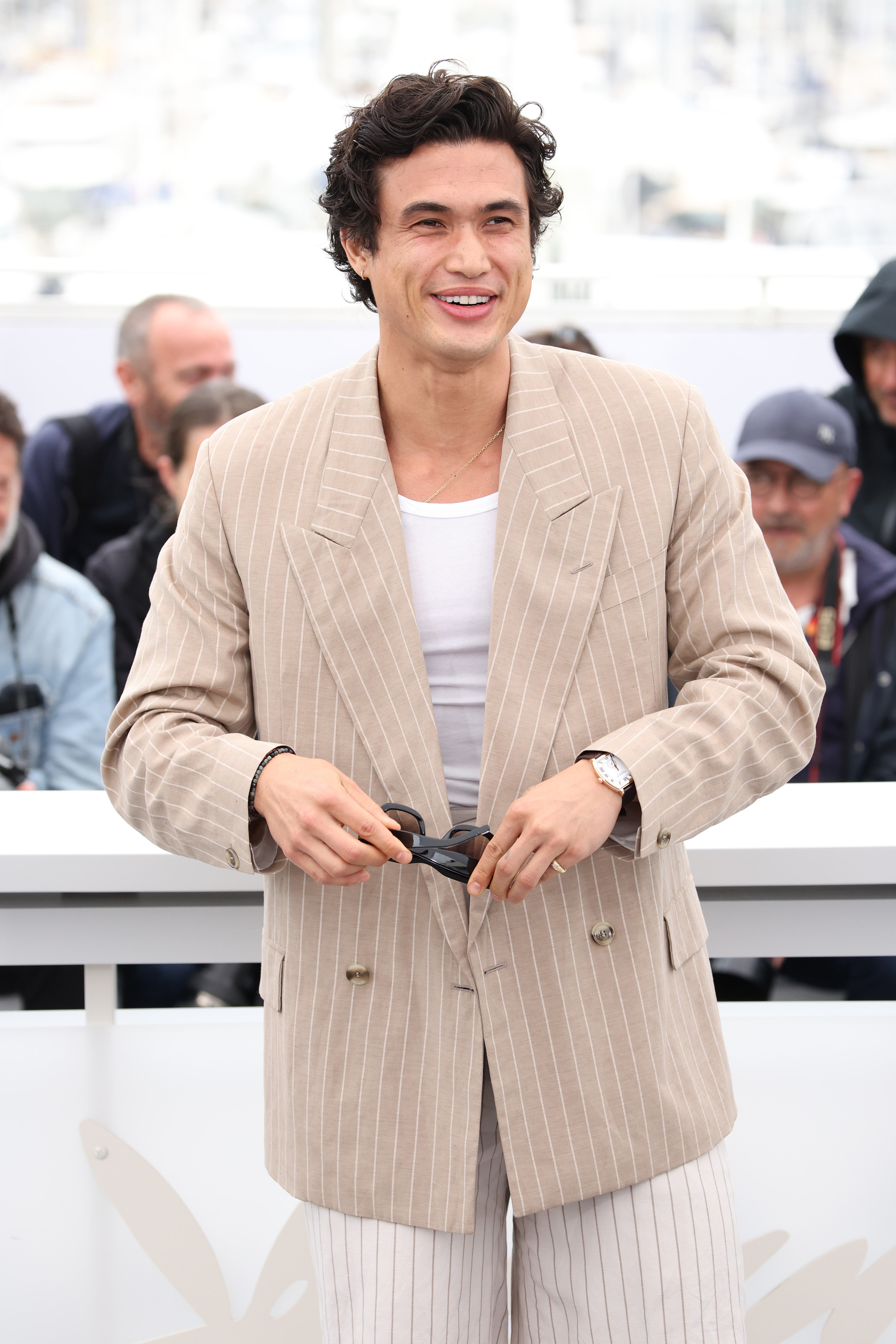 Closeup of Charles Melton on the red carpet in a casual striped blazer and striped pants