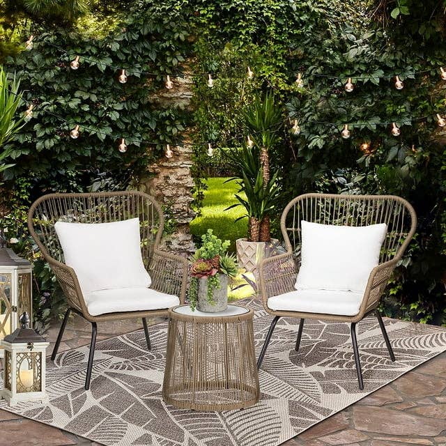 Outdoor furniture setup with two chairs, cushions, a table with plants, and a decorative lantern, in a garden setting