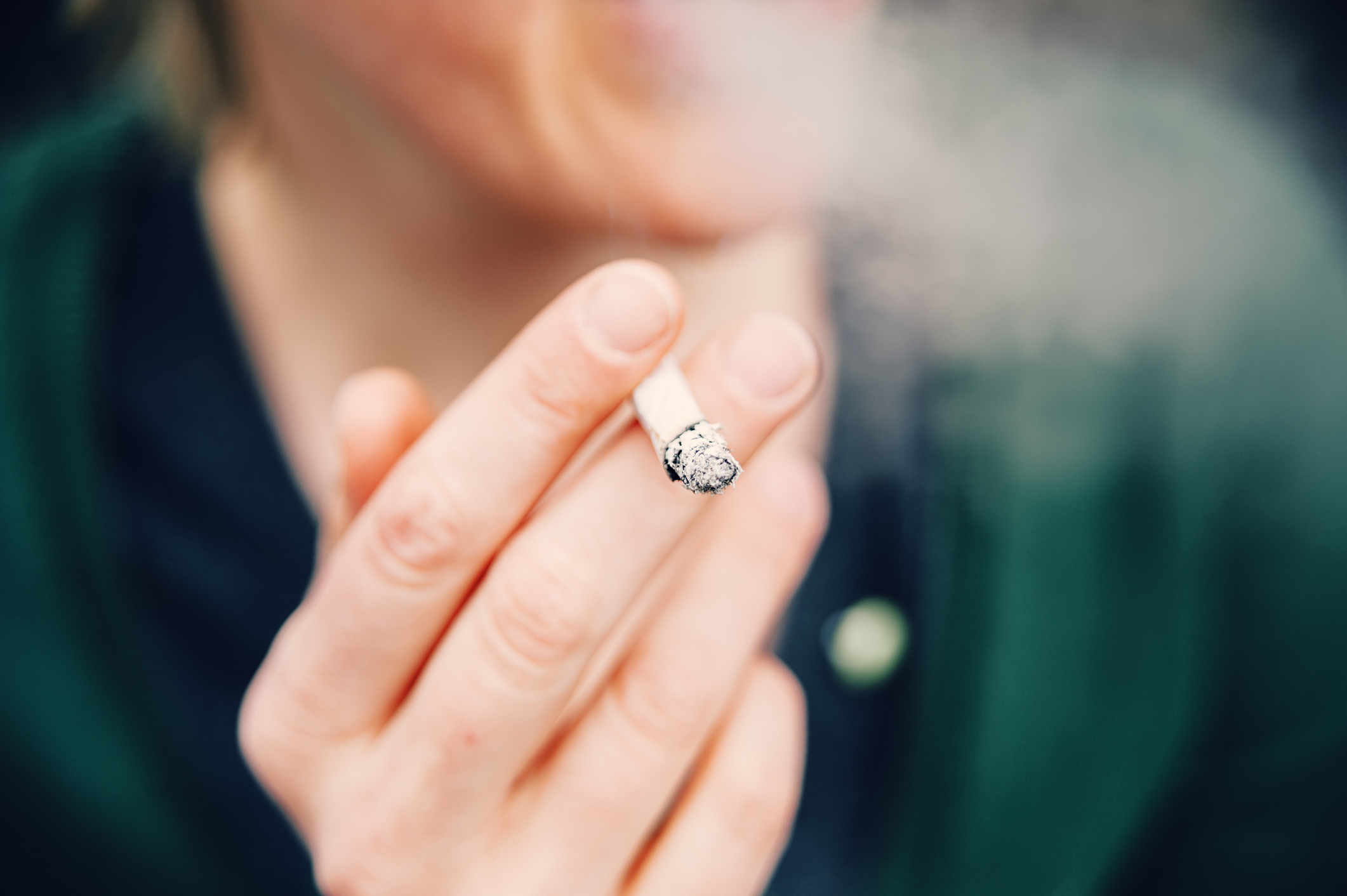 An unidentified person holding a half-smoked cigarette
