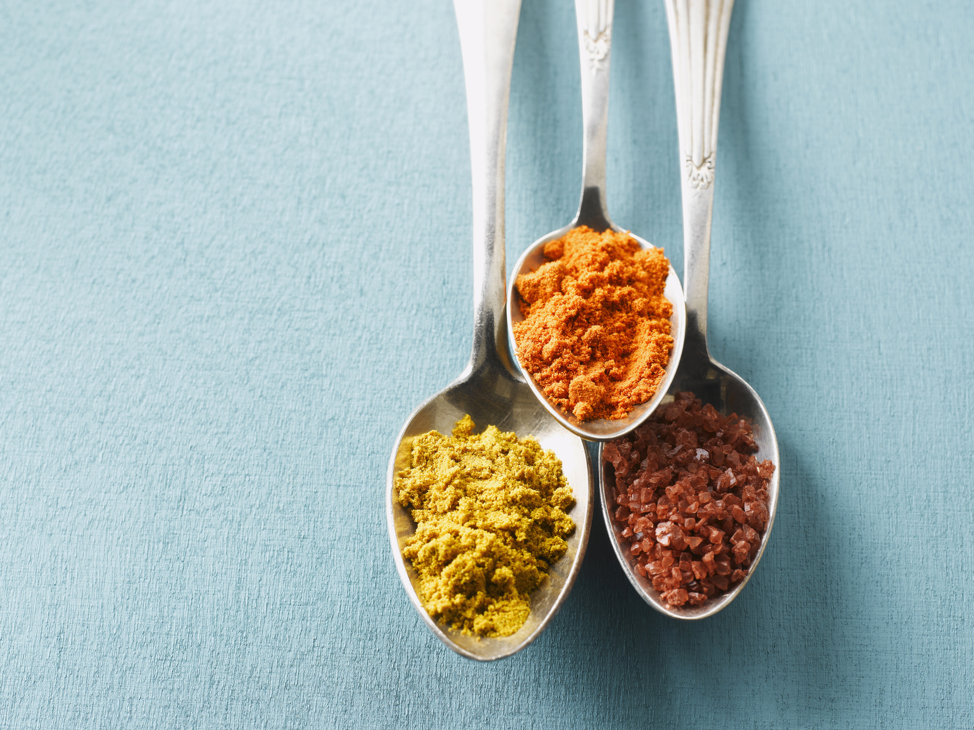 Three spoons holding different spices in each