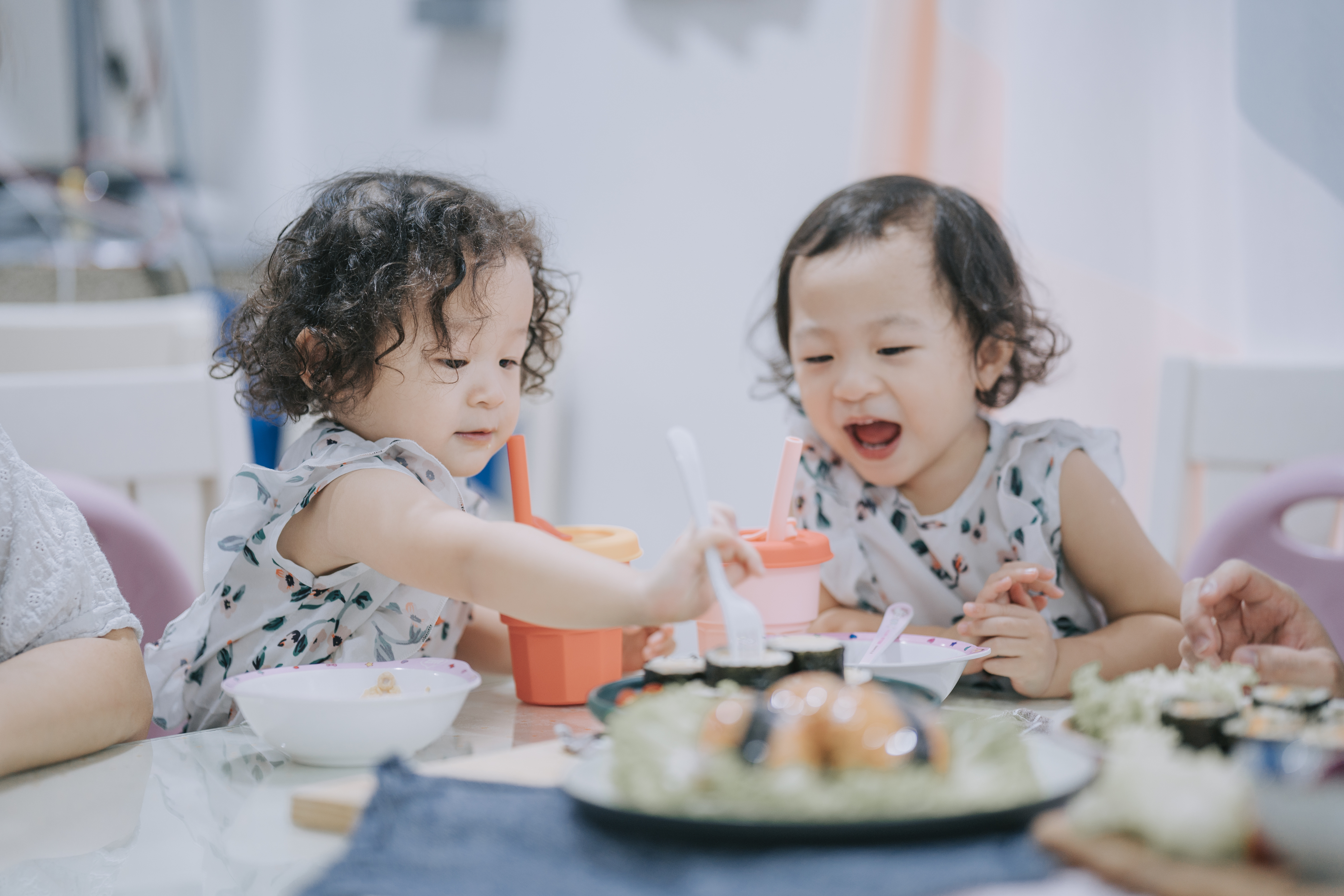 Twin toddler girls eating at the table