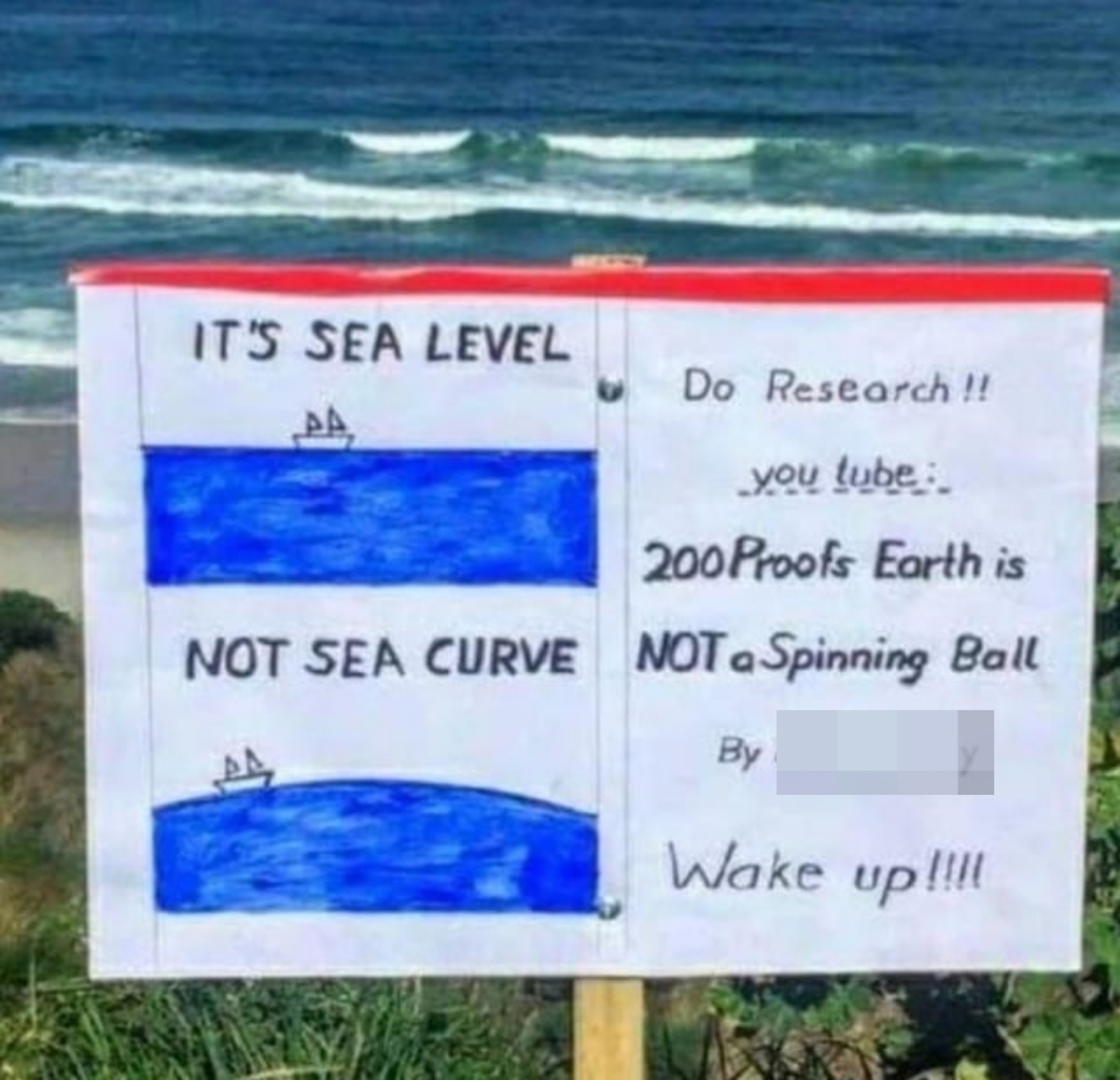 A sign by the ocean directing people to a flat earther YouTube video