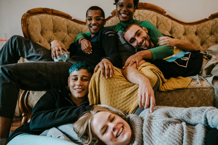A group of people are laying on each other on a couch