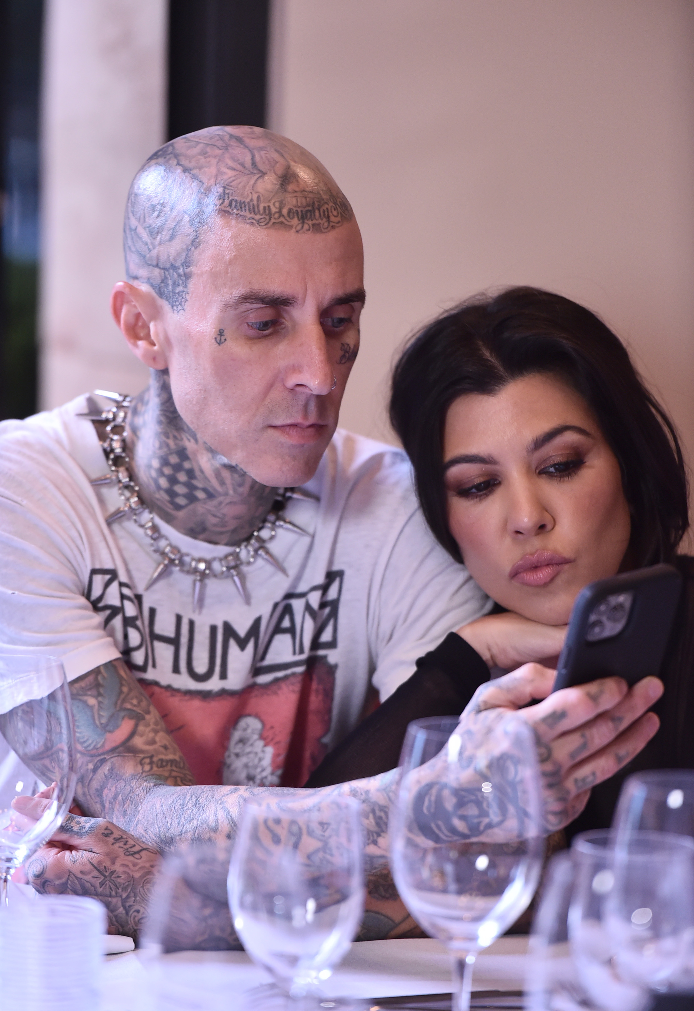 travis and kourtney at dinner looking at a phone