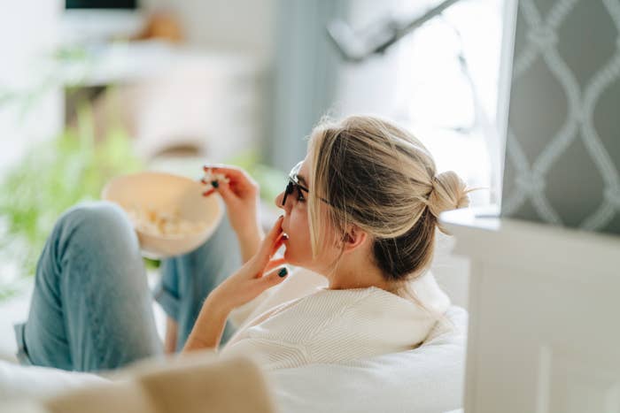 Blond woman with hair bun watching TV on a cozy sofa indoors