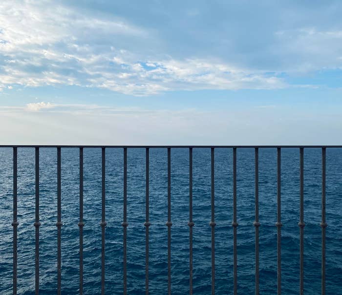 A railing in front of the ocean lining up perfectly with the horizon