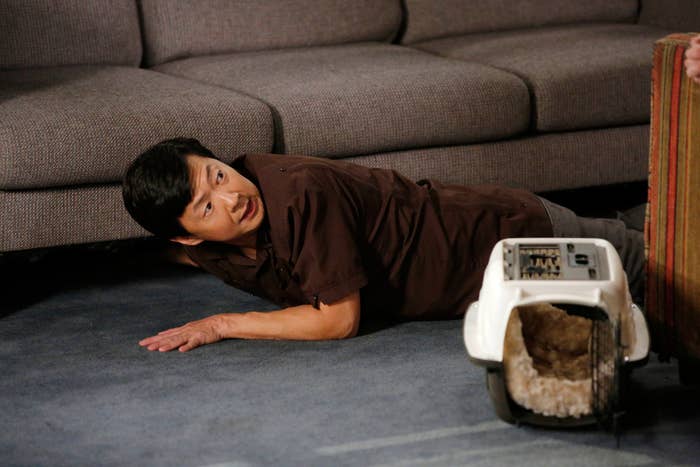 guy on the ground reaching under a sofa