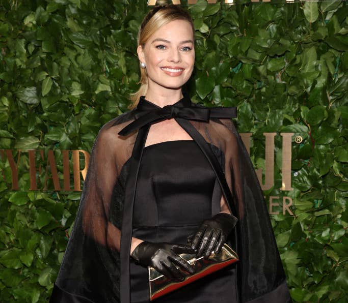 Closeup of Margot Robbie in a stapless dress and a sheer cape