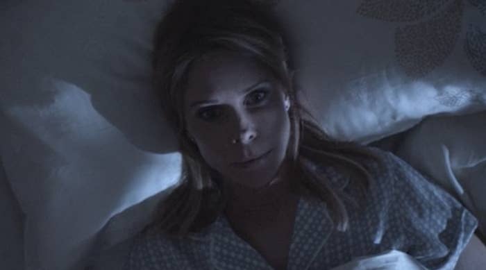 A woman lying in bed at night with eyes wide open