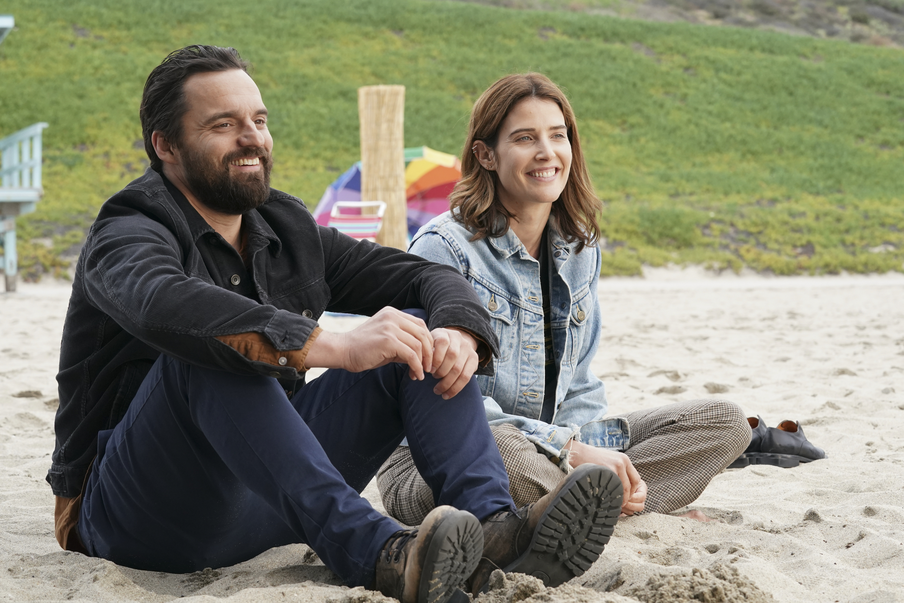 Two people sitting on a beach in a scene from &quot;Stumptown&quot;