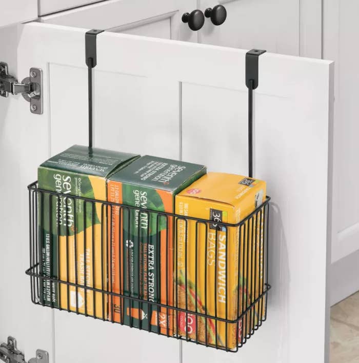 a wire rack holding wrap boxes hanging on the inside of a cabinet