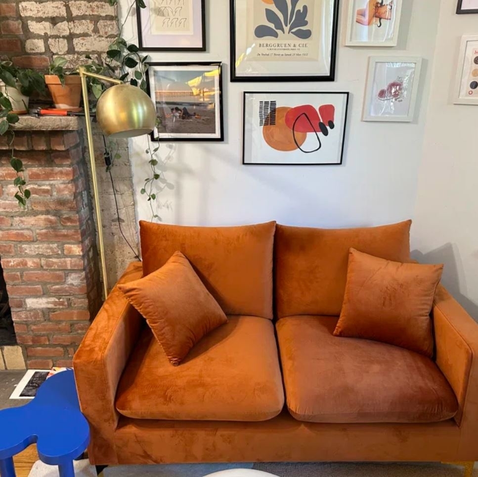 small orange velvet loveseat with two matching pillows