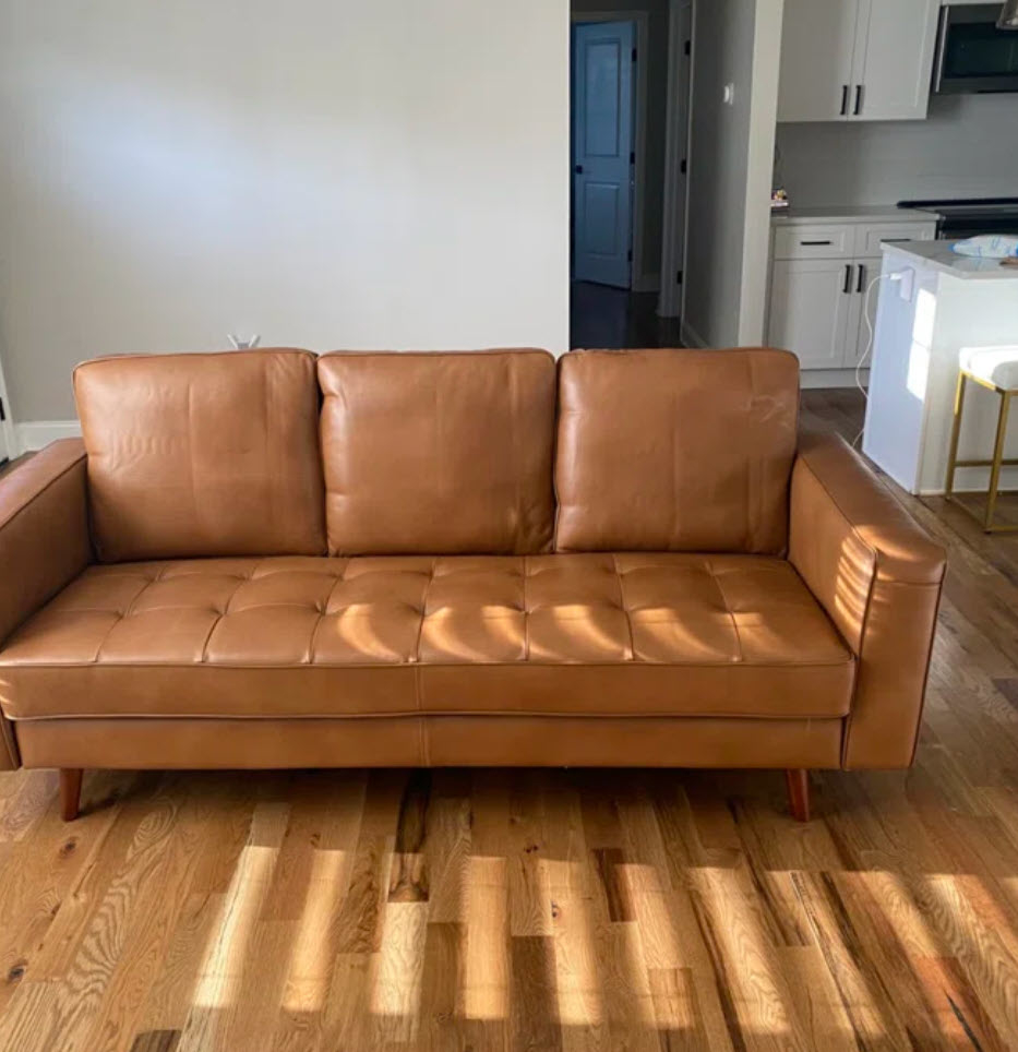 long brown leather tufted couch in living space