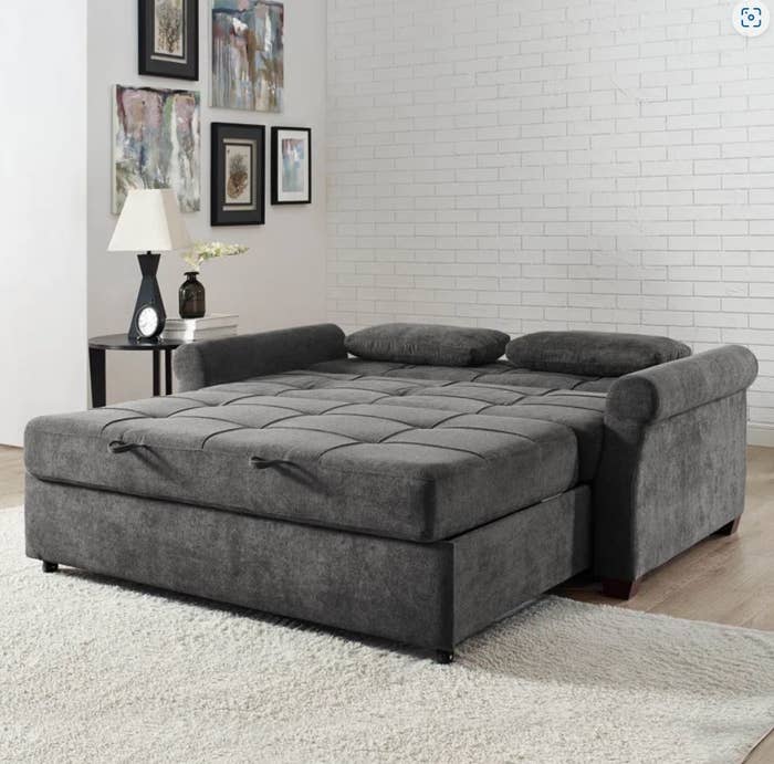 large dark grey pullout sofa bed with cushions and ottoman