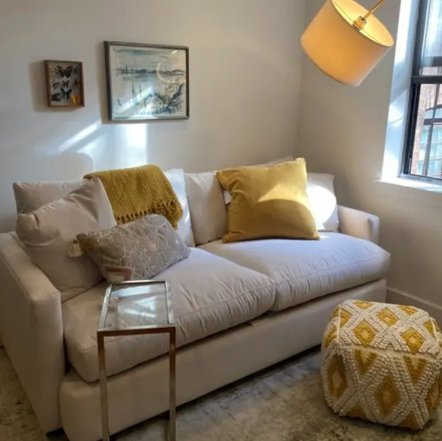 small white two-seater sofa in living room space with yellow throw accents