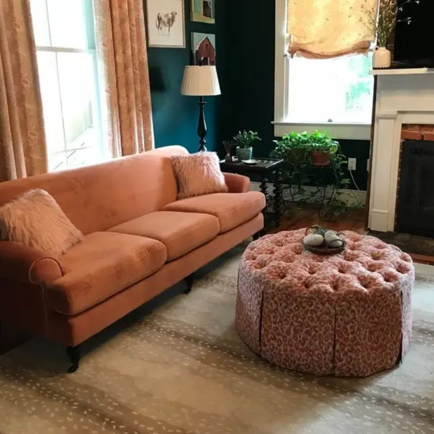 orange upholstered sofa in living room space next to a patterned ottoman
