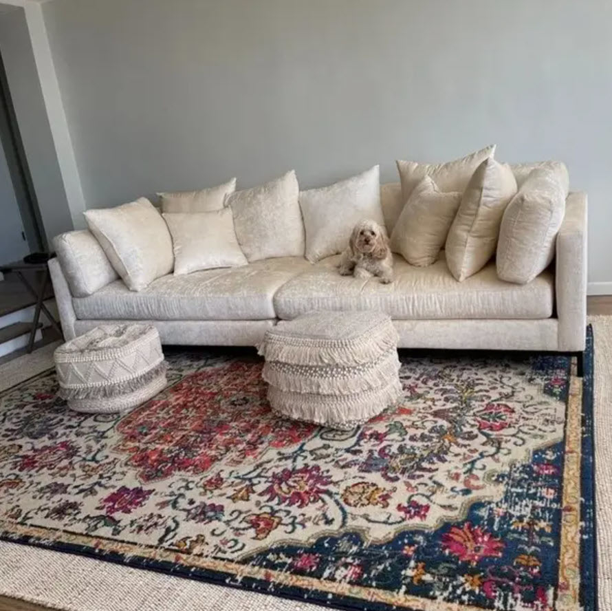 enormous light beige velvet couch with many pillows and dog on top with ottomans