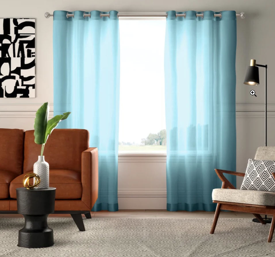 blue sheer curtain set in front of window in home