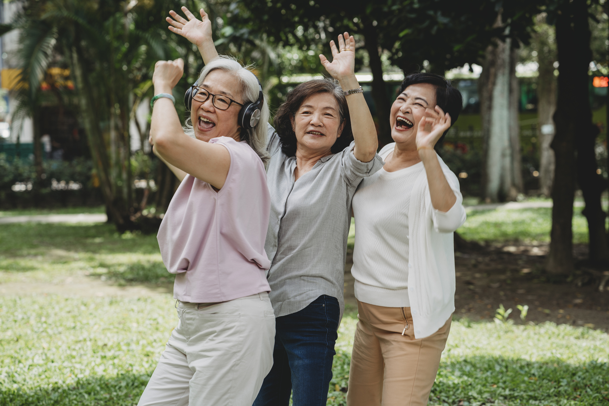 A trio of older women are dancing and laughing
