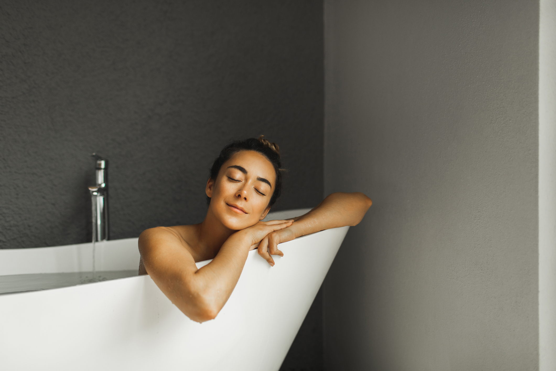 A woman is sitting in her bathtub looking relaxed