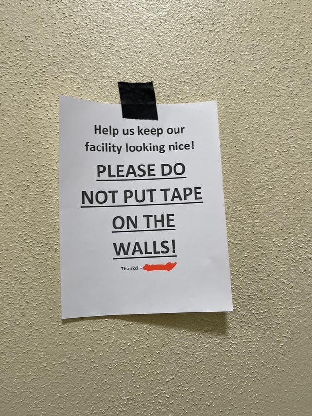 A taped sign saying, "Please do not put tape on the walls!"
