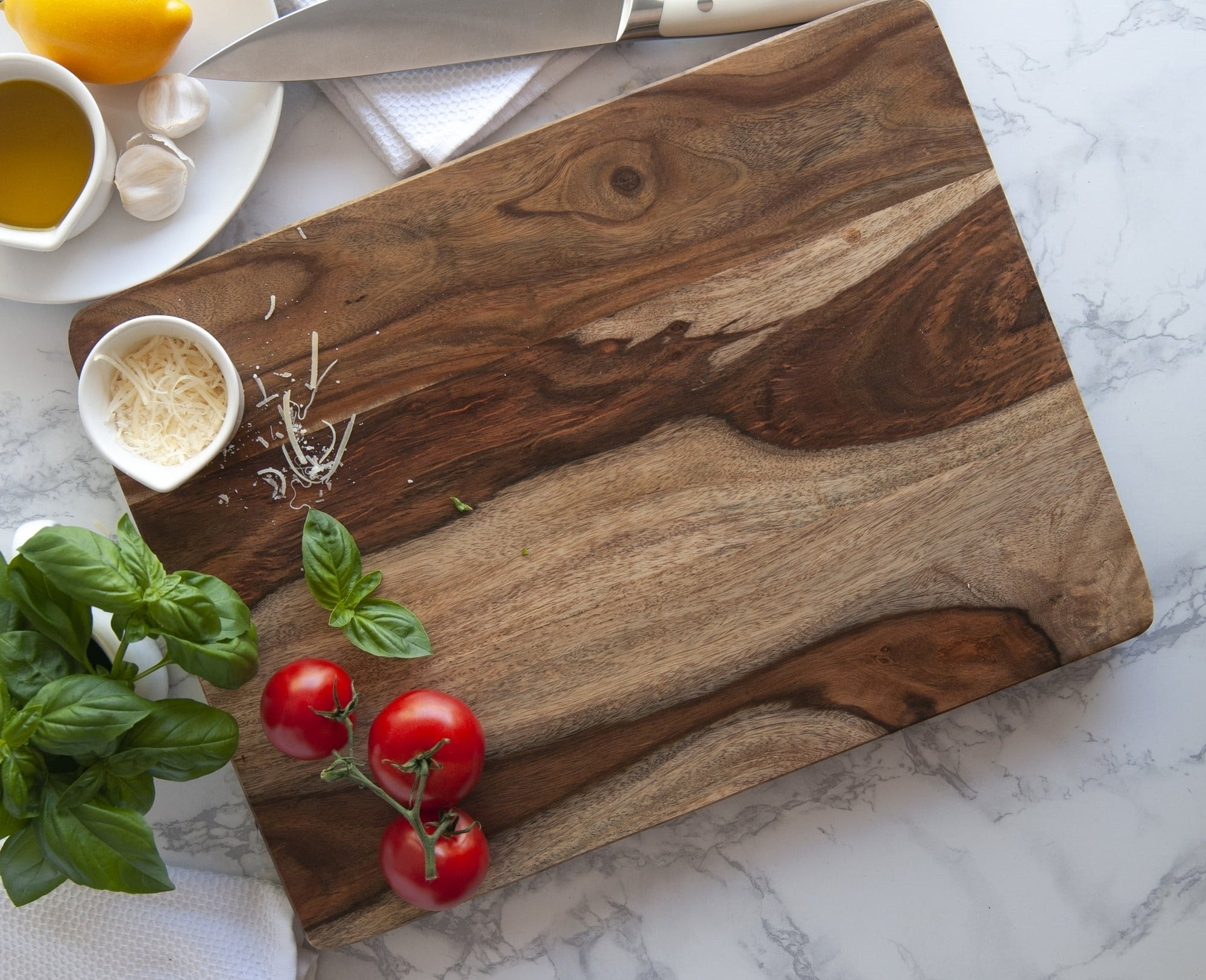 the marbled cutting board on a counter with tomatoes and basil