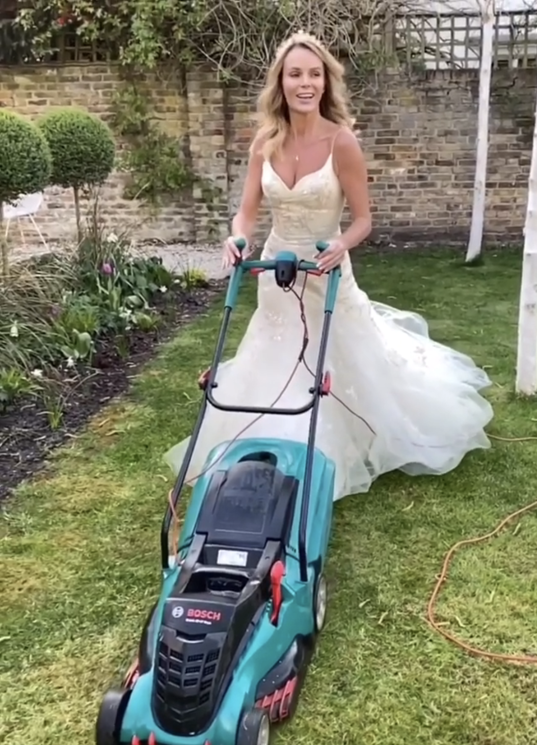 her mowing the lawn while wearing a long wedding dress