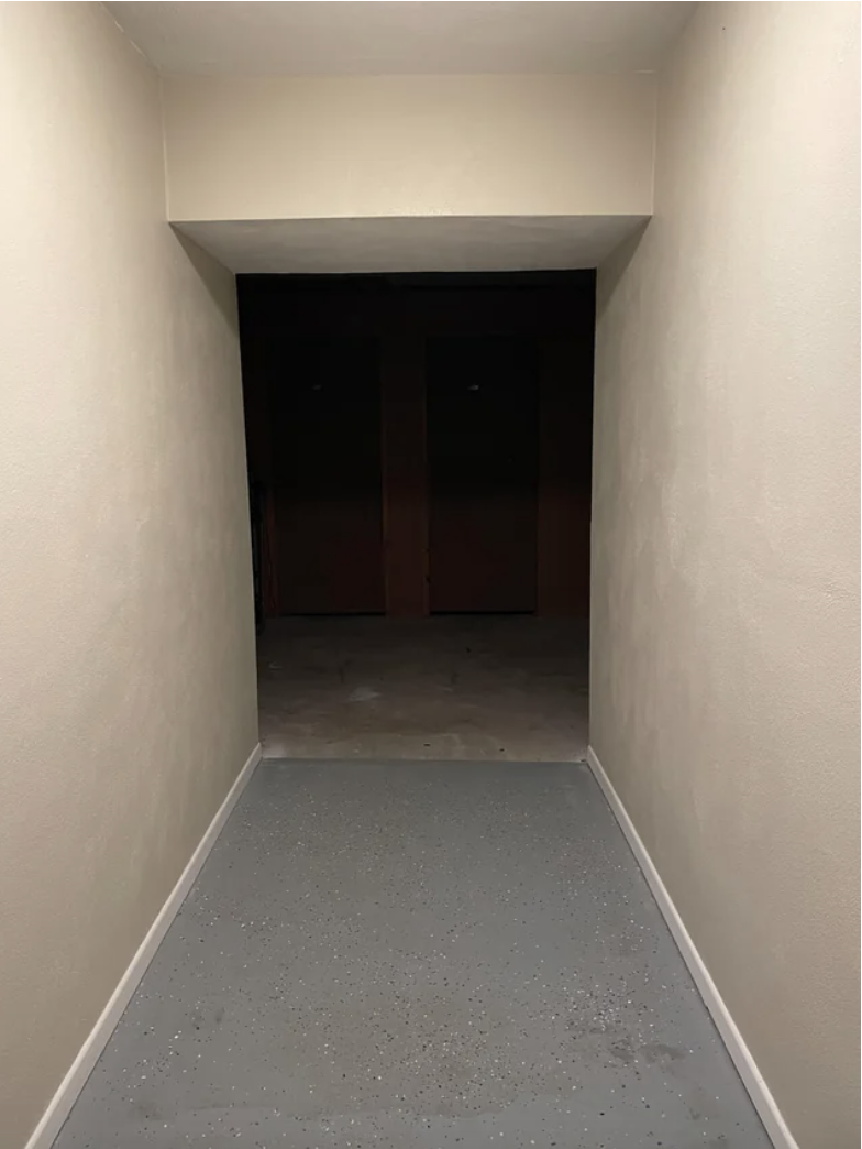 A dark, empty room with no door at the end of an empty hallway