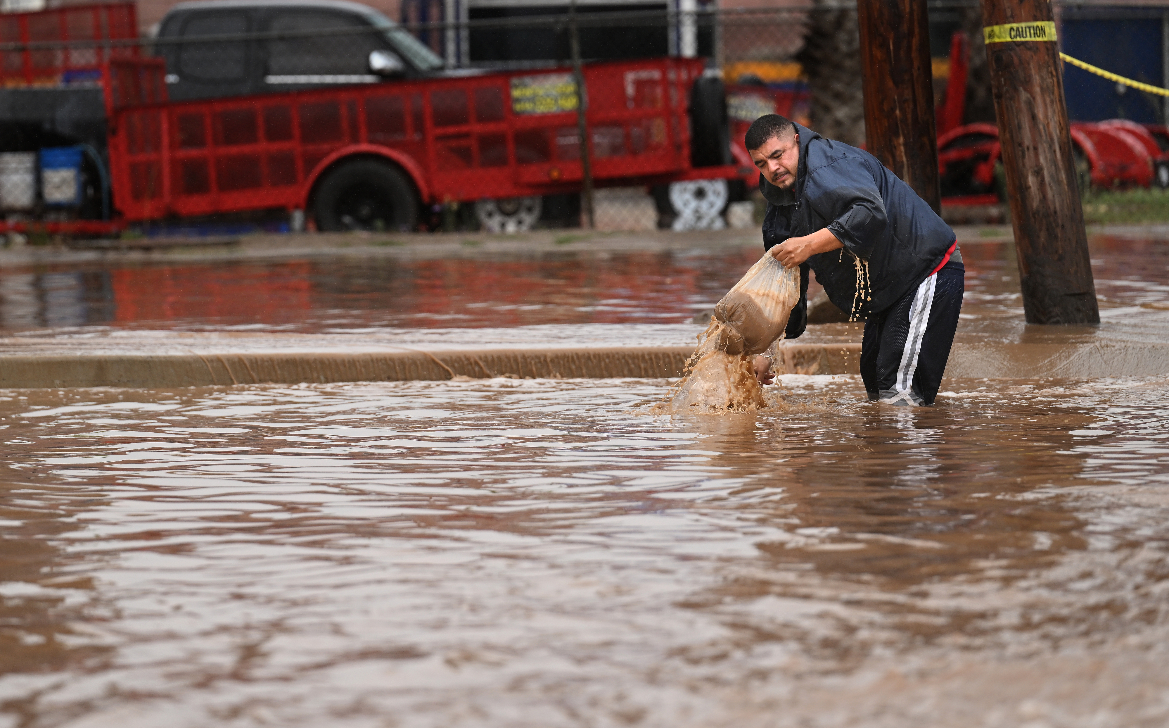 A man tries to clear a drain as Tropical Storm Hilary makes landfall in Ensenada, Mexico