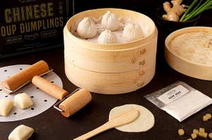 Soup dumplings in wooden basket with tools and dough out around them