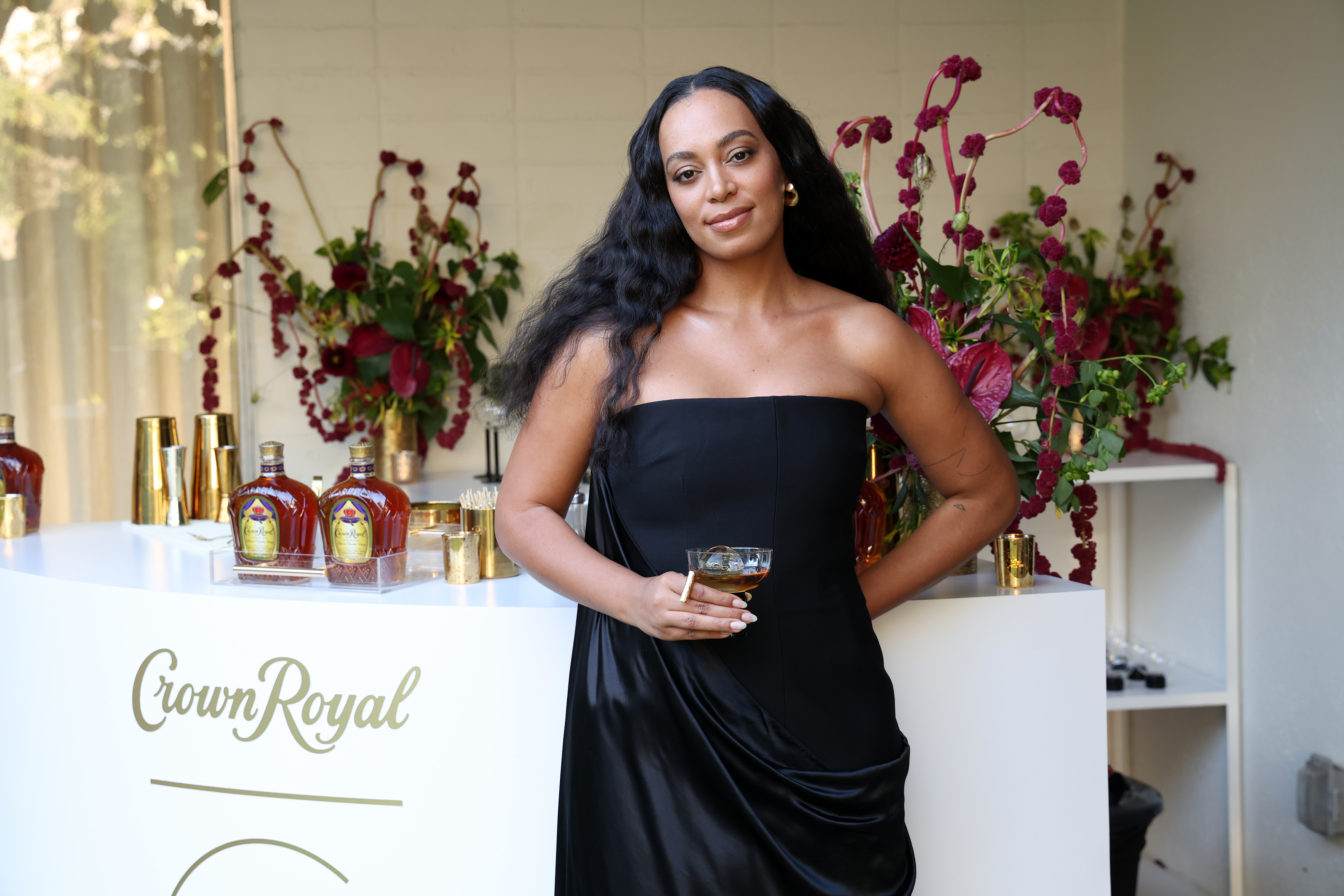 Closeup of Solange standing in front of a table of Crown Royal