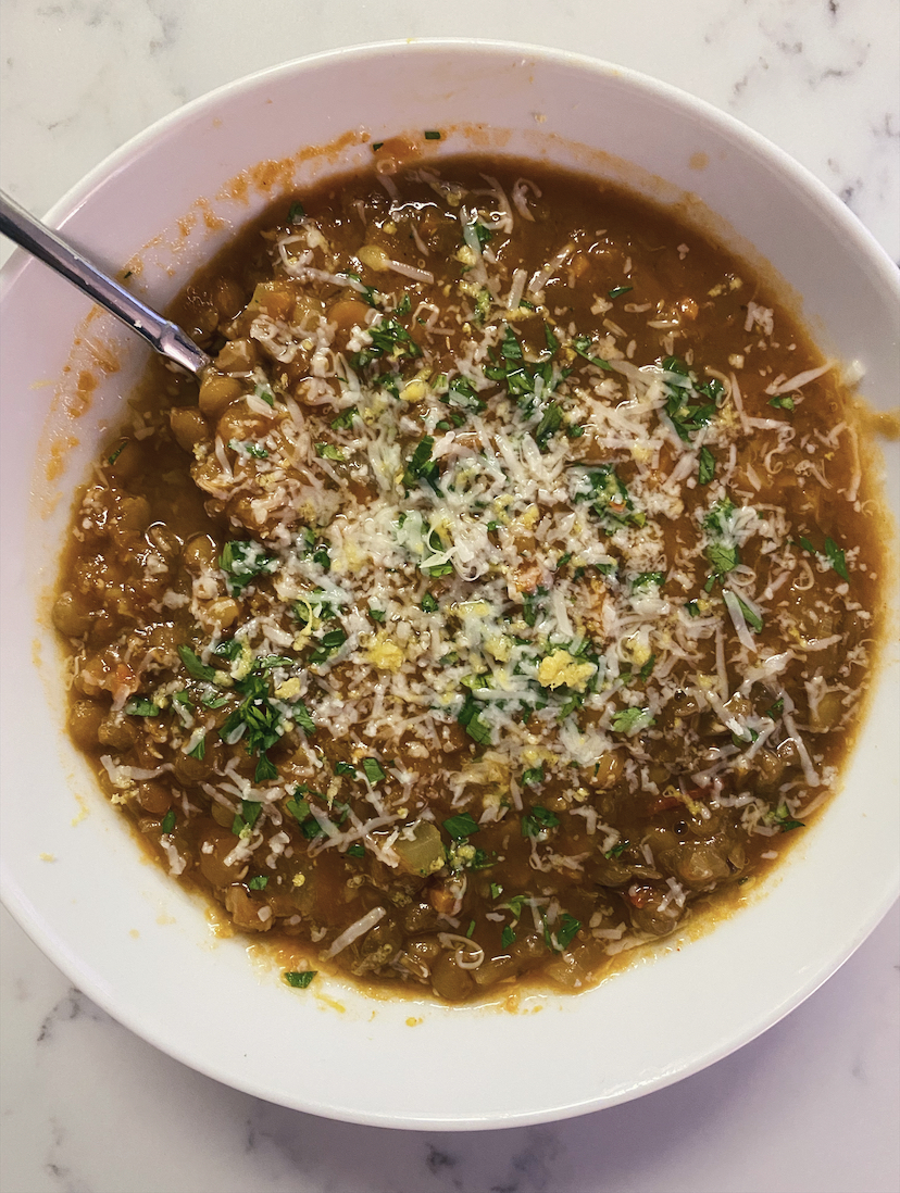 Bowl of lentil soup topped with cheese and parsley