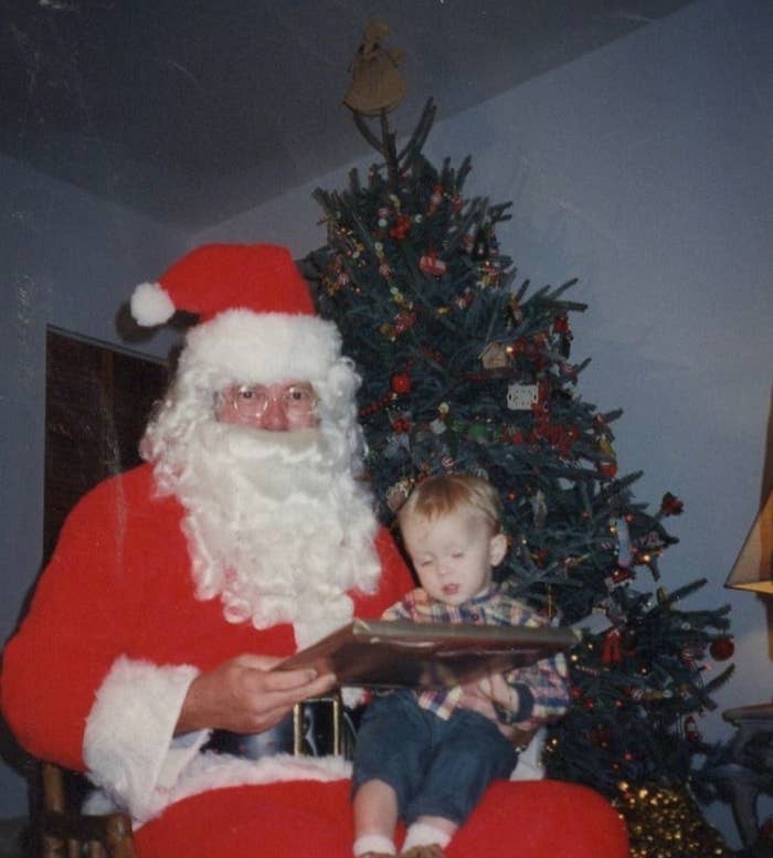 A little boy sitting on Santa&#x27;s lap in front of a Christmas tree