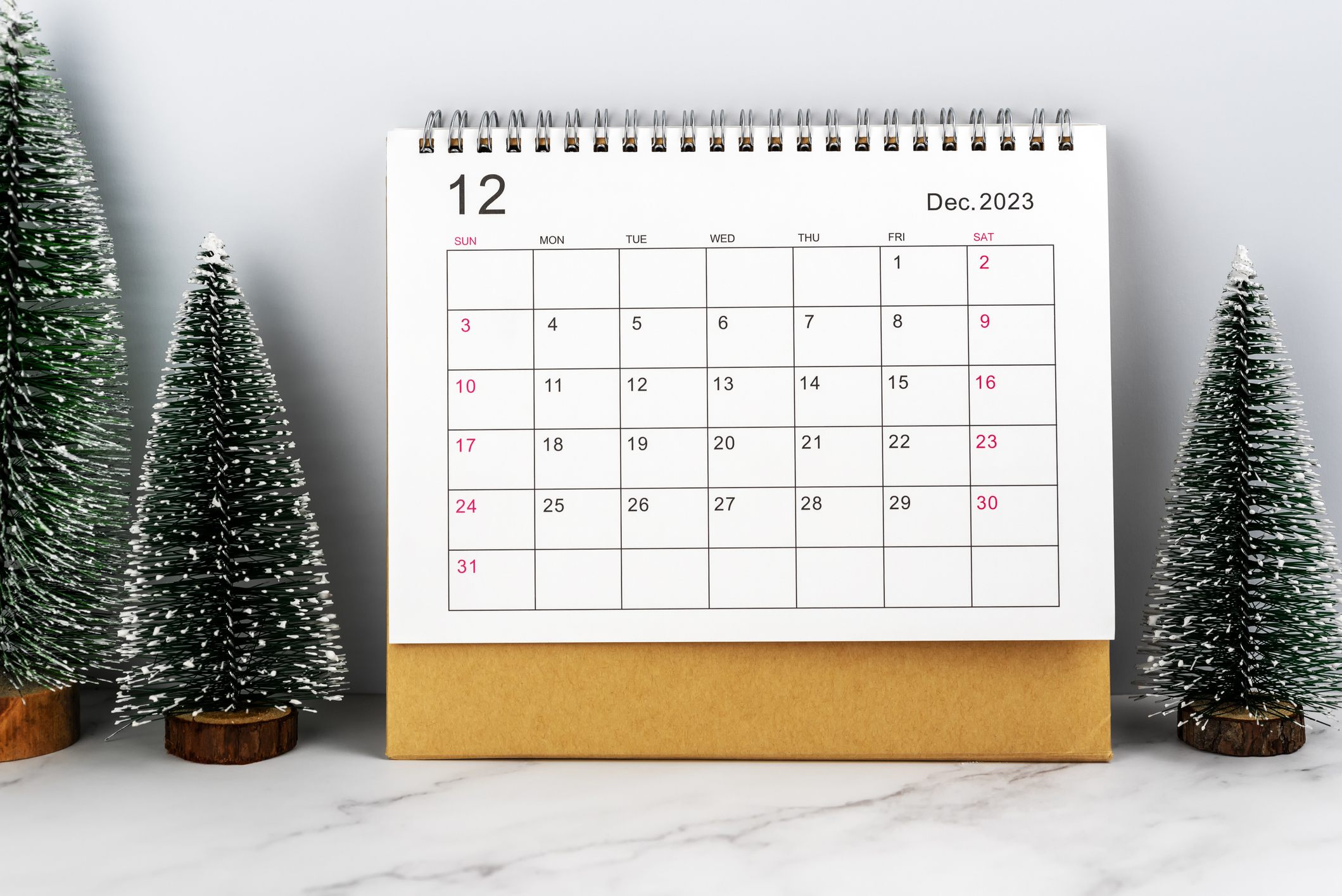 A calendar showing December 2023, with small pine trees next to it