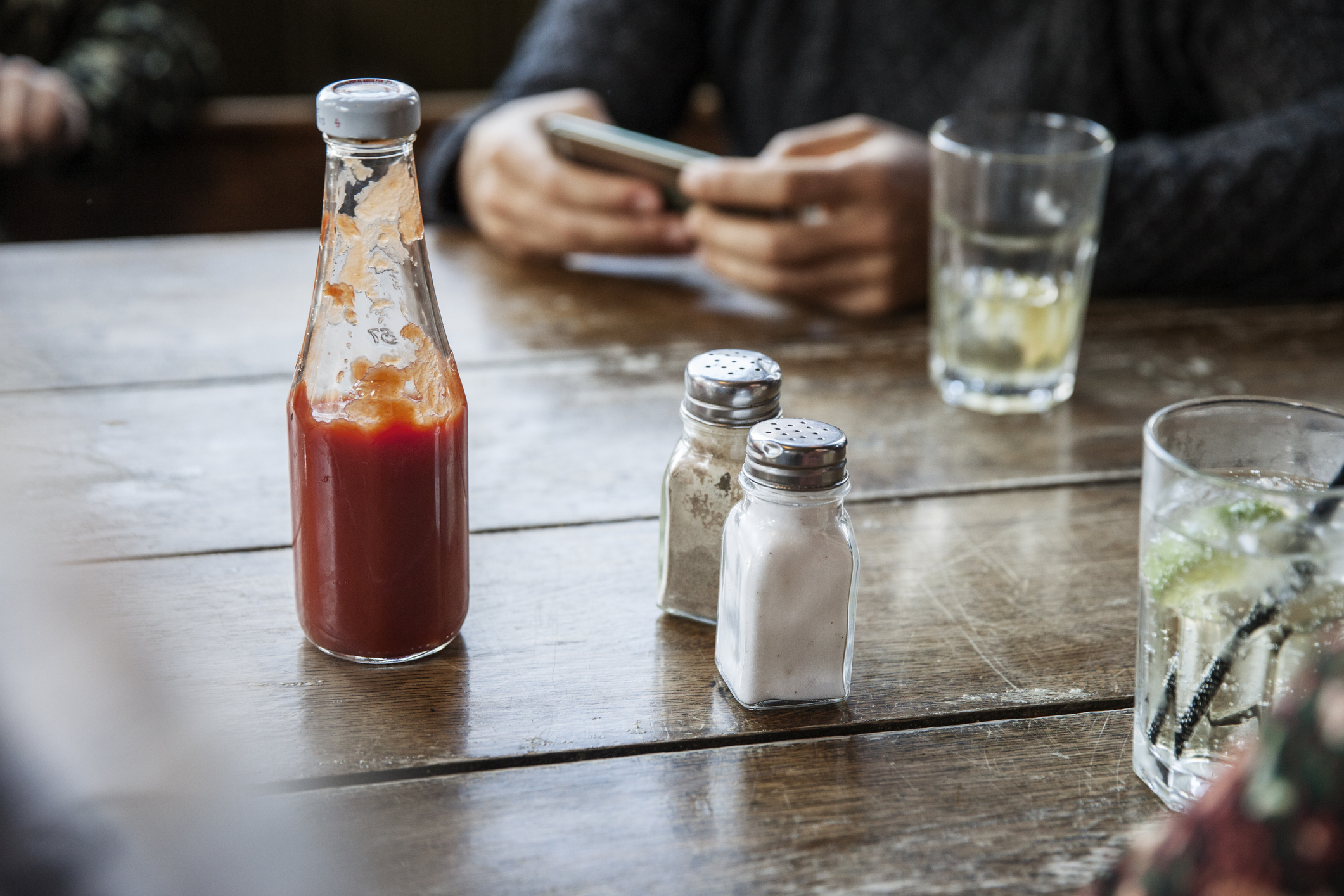 A table with a ketchup bottle, salt and pepper, and glasses on it