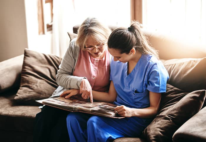 A woman showing old photos to her nurse