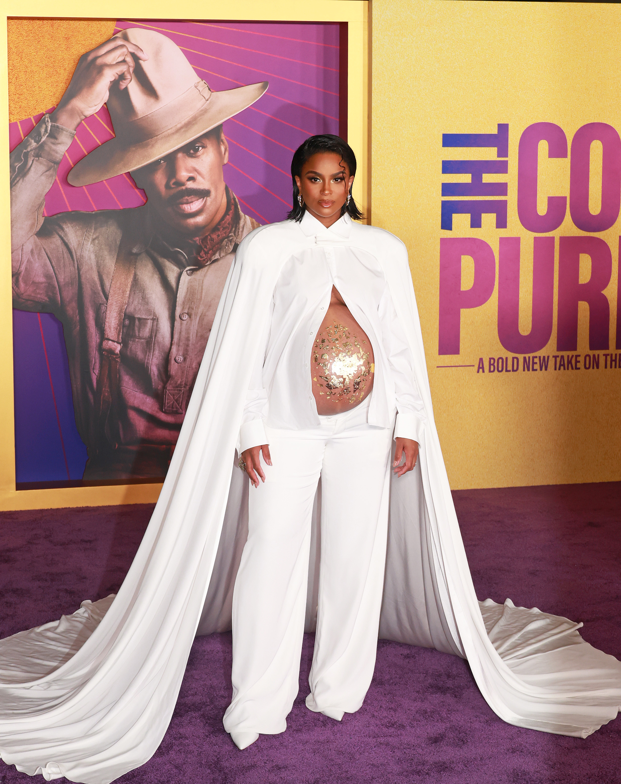 Ciara in a white pantsuit with a floor-length cape and unbuttoned to show her sparkly pregnant belly