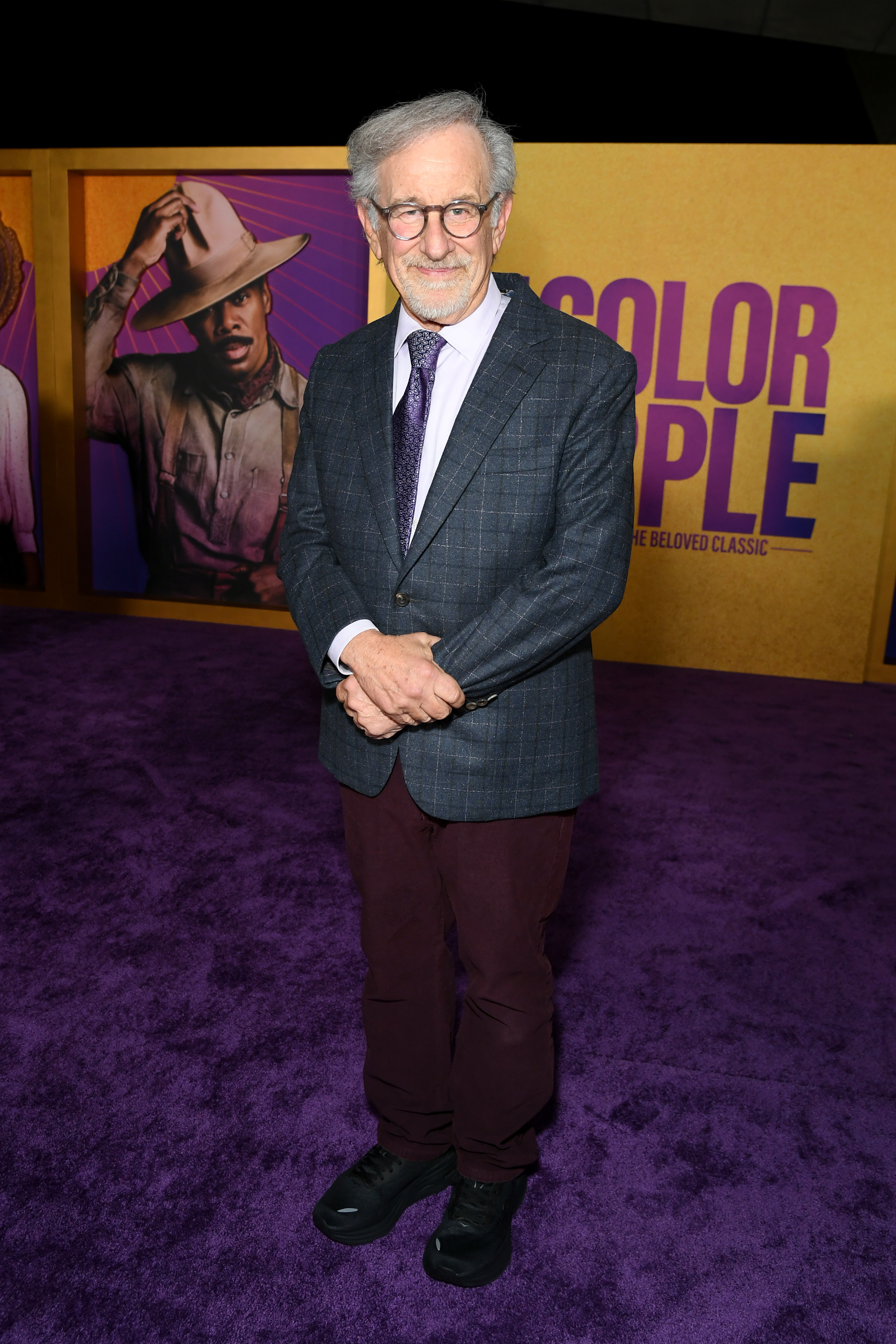 Steven in a plaid suit jacket with purple accents, purple tie, and purplish pants