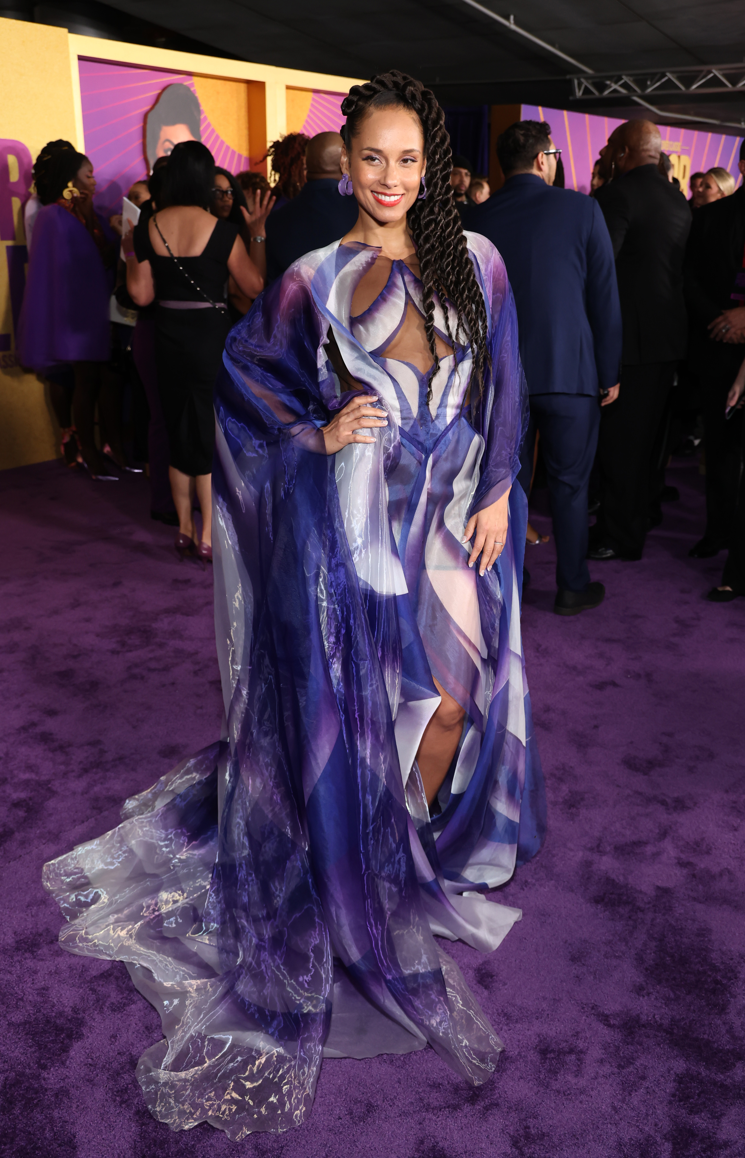 Alicia in a purple, blue, and white print gown with long flowing sleeves and a train