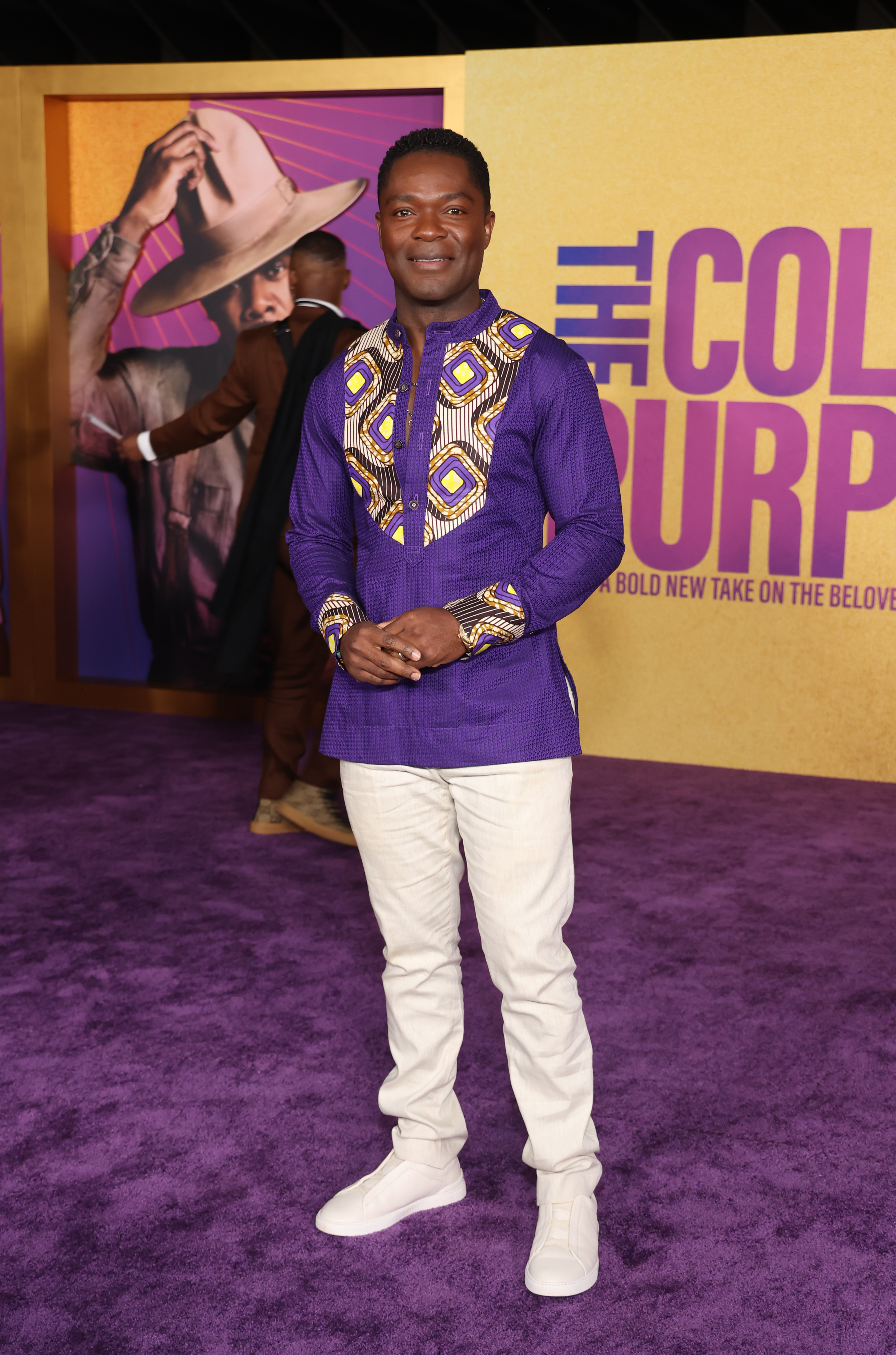 David in a long-sleeved purple print top and white pants